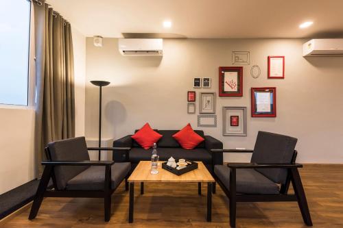 班加罗尔Townhouse MG Road,Bangalore的客厅配有沙发、两把椅子和一张桌子