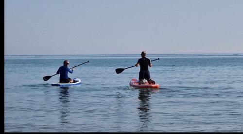 博格诺里吉斯Guest suite 50m from the beach的两个人在水中划桨板