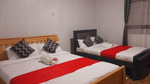 KiganjoHotfoot Homestays的一间卧室配有两张红色和白色床单