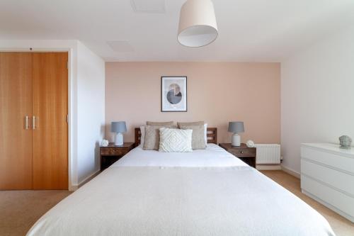 伦敦The Stratford Apartment的卧室配有一张白色的大床和两张桌子