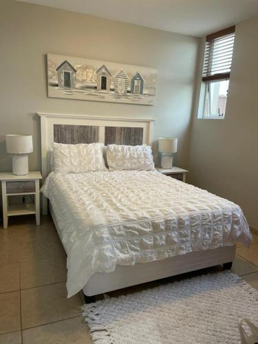 马盖特Dawn's Apartment的卧室配有一张白色床、两张桌子和两盏灯。