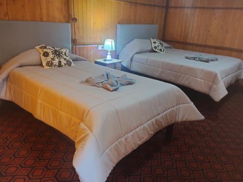 Cachorathe wooden house choquequirao的两张位于酒店客房的床,配有毛巾