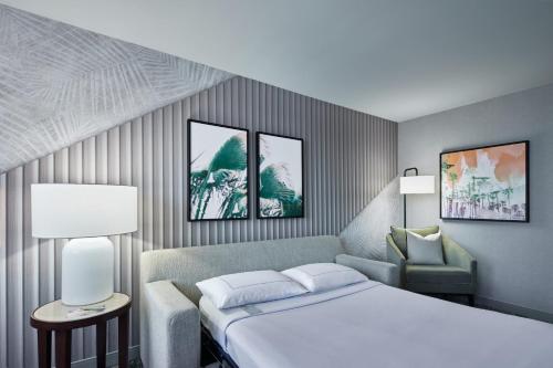 安纳海姆Hotel Fera Anaheim, a DoubleTree by Hilton Hotel的配有一张床和一把椅子的酒店客房