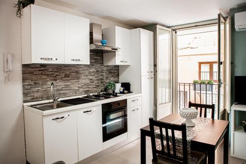 卡塔尼亚Ruggero Settimo - Holiday Houses的小厨房配有白色橱柜、餐桌和用餐室