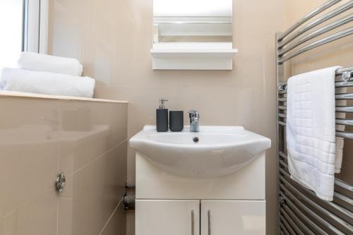 克劳利19A Apartment- Stylish & Cozy 1BR in The Heart of Crawley的白色的浴室设有水槽和毛巾。