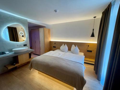 塞尔瓦迪加尔代纳山谷Hotel Des Alpes的一间卧室配有床、水槽和镜子
