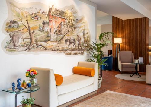 洛迦诺Boutique-HOTEL REMORINO, a Private Selection Hotel的大堂设有白色的沙发和墙上的绘画