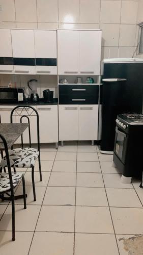 加拉尼温斯Apê da VAN acomoda até 7 pessoas的厨房配有白色橱柜和黑色冰箱。
