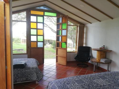 SutamarchánCABAÑA LOS JUANES的一间设有两张床的房间和一个带彩色玻璃的门