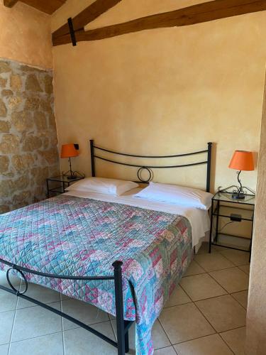 MaenzaLa fattoria di Carlotta的一间卧室配有一张床和两张带台灯的桌子。