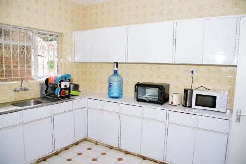 内罗毕Jabulani Nairobi Backpackers Hostel的厨房配有白色橱柜、水槽和微波炉