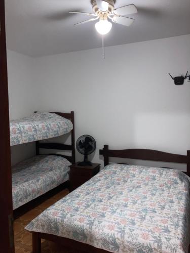 乌巴图巴Apartamentos Petrópolis的一间卧室配有两张床和吊扇