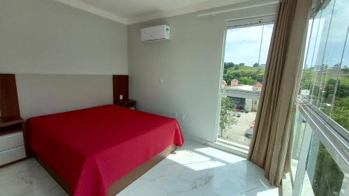 皮拉图巴Encantador Apto NOVO, climatizado e confortável - 200m das Thermas的一间卧室设有红色的床和大窗户