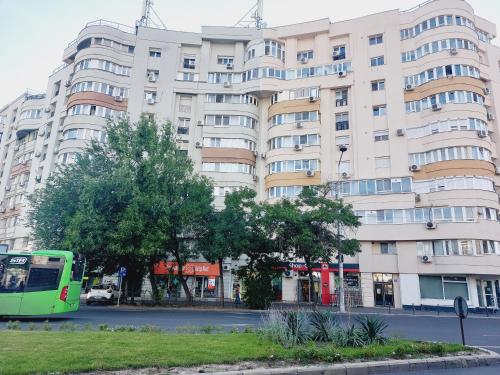 布加勒斯特Cozy apartment in the center of Bucharest的停在大建筑前面的绿色巴士
