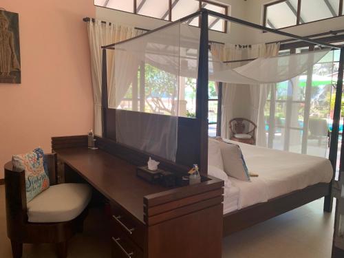 蓝赛特海滩Ban Laem Set - Beachfront Private Luxury Villa的一间卧室配有一张天蓬床、一张桌子和一把椅子