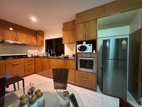 芭东海滩Hideaway House Patong的厨房配有木制橱柜和不锈钢冰箱。