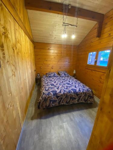LégnaLe petit chalet du mouralet的木制客房内的一间卧室,配有一张床