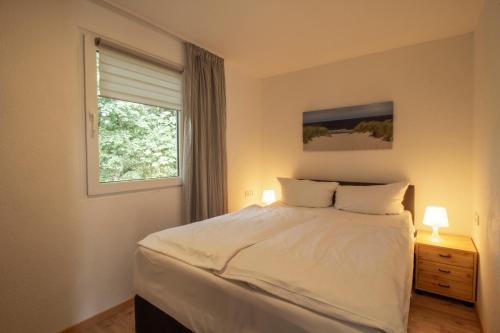 科尔斯万特Usedomer Bungalows的卧室配有白色的床和窗户。