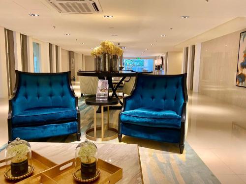 伊洛伊洛Unit 3J Signature Suites, Lafayette Megaworld的客厅配有两张蓝色椅子和一张桌子