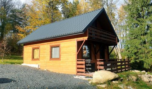 ZachełmieOmszałe Głazy的一间拥有黑色屋顶的小型小木屋