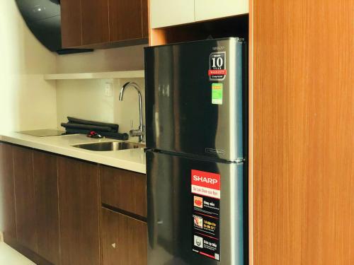 海阳Apec Mandala hotel & suites Hải dương的带木制橱柜的厨房内的黑色冰箱
