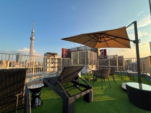 东京HOTEL TOMOS ASAKUSA的一个带椅子和遮阳伞的庭院和艾菲尔铁塔