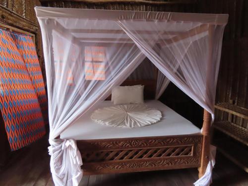 帕杰Drifters Zanzibar的一张带白色床单和枕头的天蓬床