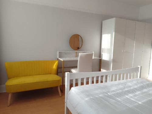 SurbitonTwin home with free parkings, Surbiton, Kingston upon Thames, Surrey, Greater London, UK!的一间卧室配有一张床和一张黄色椅子