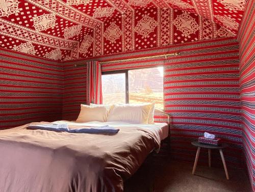 瓦迪拉姆Bedouin Tribe Camp Wadi Rum的一张位于一个红色和黑色墙壁的房间的床铺