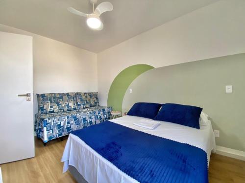 伯迪亚哥FLAT COM VARANDA E SERVIÇOS NO RIVIERA GREEN的一间卧室配有一张带蓝色枕头的床和一张沙发。