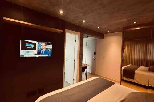 布卢梅瑙Loft de Luxo na Vila Germânica的一间卧室配有一张床,墙上配有电视
