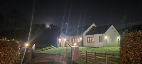 巴洛赫Auchendennan Farm Self Catering Cottages的夜晚的房子,前面有灯