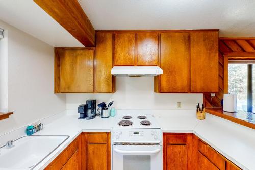 LakeshoreHuntington Lake Condo #38的厨房配有木制橱柜和白色炉灶烤箱。