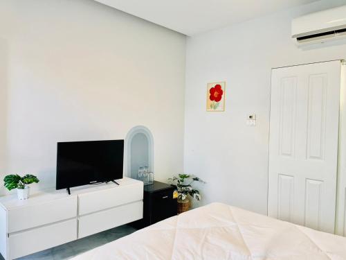 清迈Sky View Home and Hostel Chiangmai的一间白色卧室,配有电视和白色梳妆台