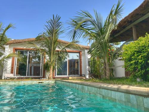 姆布尔Keur Ama的棕榈树屋前的游泳池