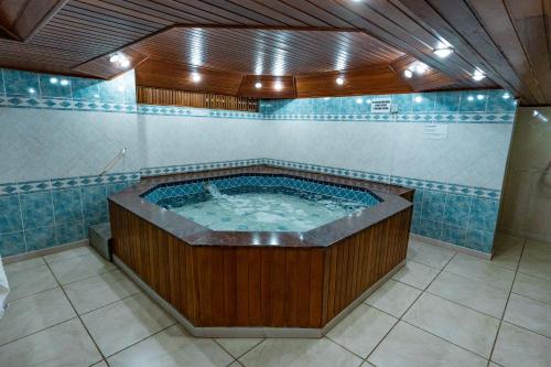 弗洛里亚诺波利斯HANNA San Diego Apart Hotel的浴室设有蓝色瓷砖,配有按摩浴缸。