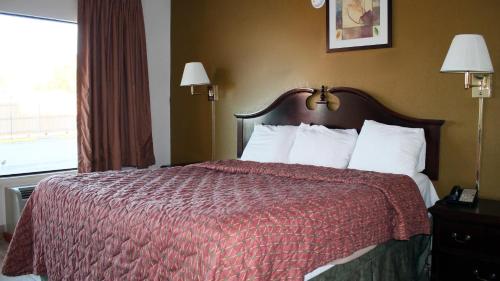 泰勒Royal Inn & Suites的酒店客房,配有一张红色棉被的床