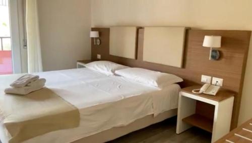 克罗托内hotel villaggio Casarossa的一间卧室配有一张白色的床,在床头柜上配有电话