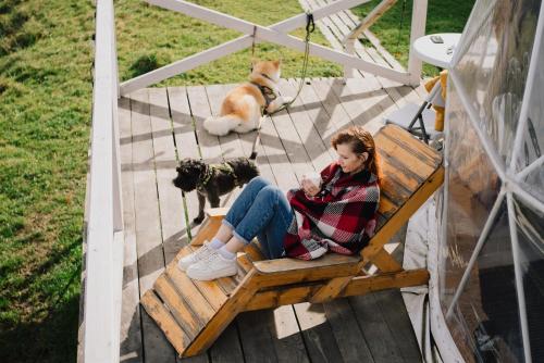 Готель Еко Сфера的和狗一起坐在长凳上的女人