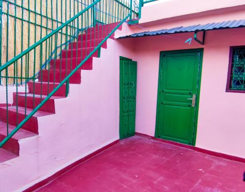 非斯Fes Hostel Zaouia的粉红色建筑的两扇绿色门,设有楼梯