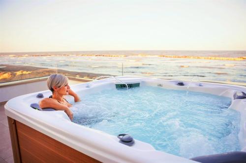 里米尼You & Me Beach Hotel的坐在热水浴缸中的女性,享有海景