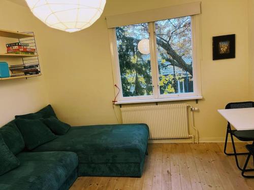 胡丁厄Nice two room flat 15 minutes from Stockholm C .的客厅设有绿色沙发和窗户。