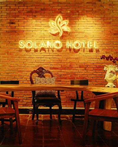 利帕Solano Hotel & Resort At Casa Ysabel的一张带椅子的木桌和砖墙上的标志