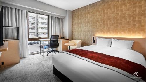 松山松山大和鲁内酒店的酒店客房设有一张大床和一张书桌。