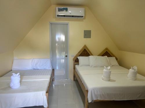 锡基霍尔Dwarf Guest House的小客房内的两张床,配有白色床单