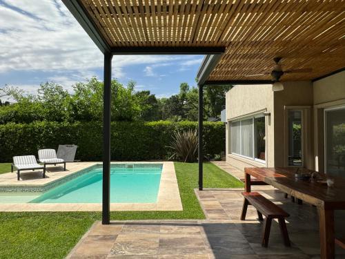 Del VisoDivina casa con parque pileta en mini barrio cerrado.的一个带桌子和游泳池的庭院