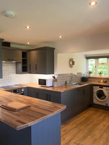 奥斯威斯3 Bedroom Bungalow in Llanrhaeadr Ym的厨房配有灰色橱柜和台面