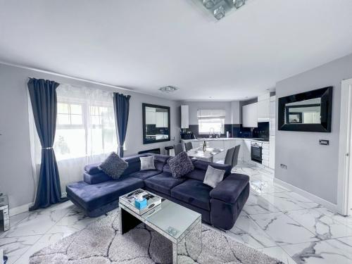 埃奇韦尔2 Double Bedroom Apartment in Edgware, London的一间带蓝色沙发的客厅和一间厨房