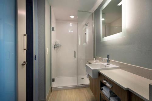 新士麦那海滩SpringHill Suites by Marriott New Smyrna Beach的浴室配有盥洗盆和带镜子的淋浴