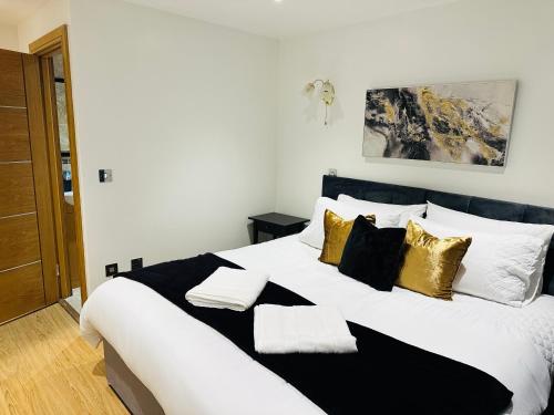 克罗伊登Bright 2 Bedroom *2 Bathroom* 10 mins to East Croydon的一张带黑色和金色枕头的大型白色床